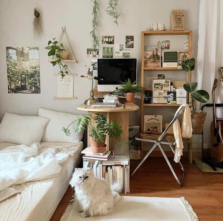Natural wood tones and white dominant living room home office with artificial plants and a white cat creating cozy atmosphere