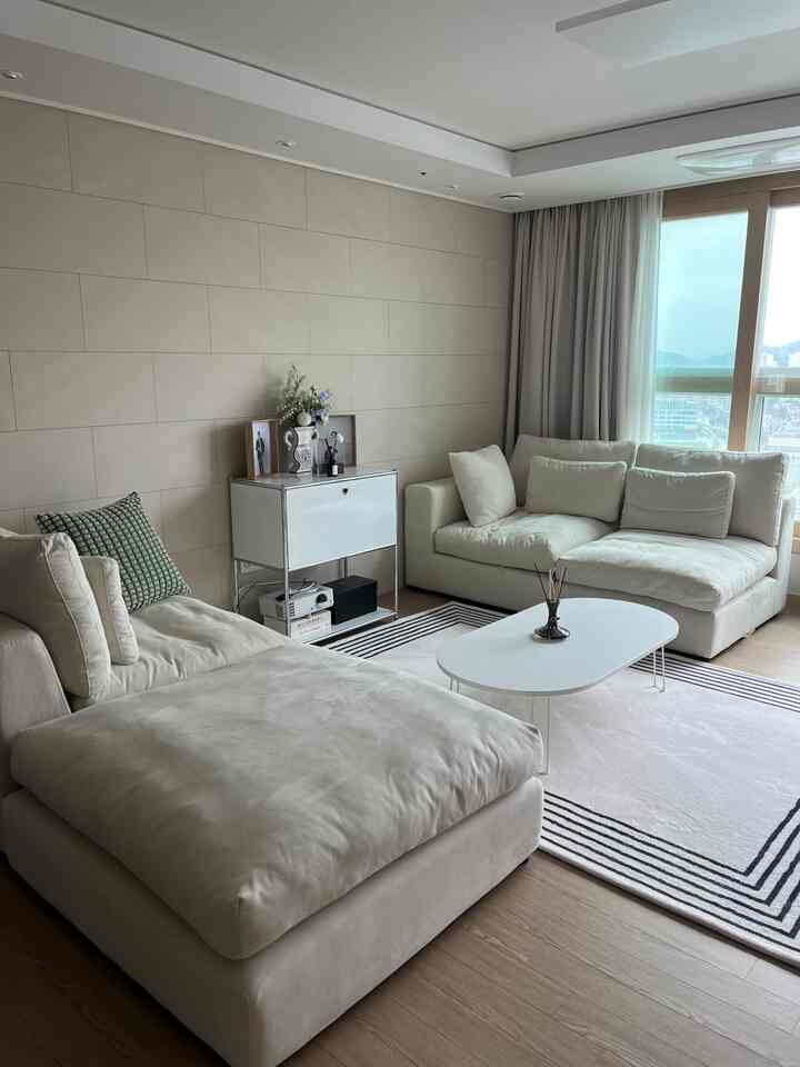 明るいナチュラルカラーのリビング、白いソファとシンプルなコーヒーテーブルが配置されたモダンな空間