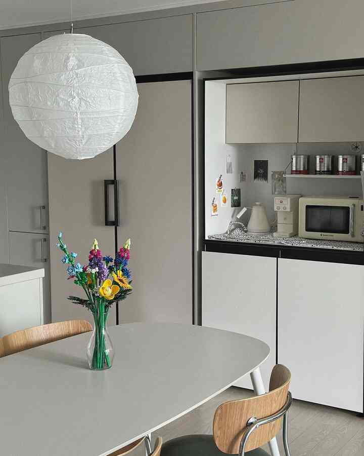 白とベージュの落ち着いた色調のダイニングルーム、ダイニングテーブルと椅子、ペンダントライトが配置された印象的な空間