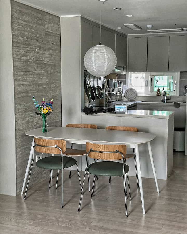 ホワイトとグレーのトーンのキッチン、モダンなダイニングテーブルとチェア、レゴの花束がアクセントのシンプルなインテリア