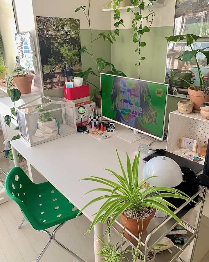 White and green toned studio apartment desk in Mid-Century Modern style, featuring various plants in a tidy home office space