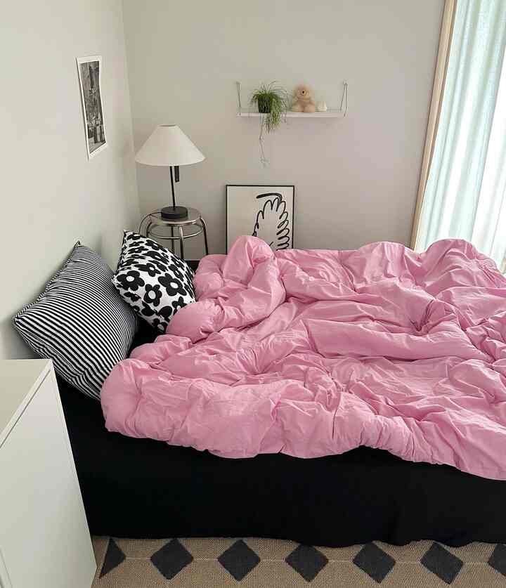 White and pink toned bedroom featuring a black bed with pink duvet cover in a simple and clean atmosphere