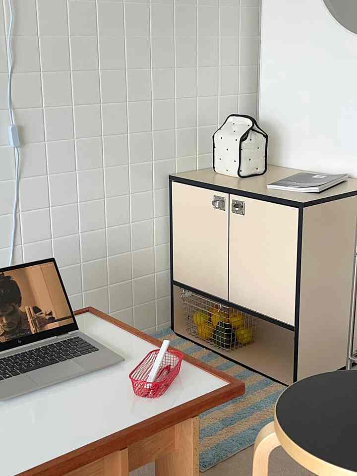 白いタイルの壁とベージュの収納キャビネットが配置されたモダンなホームオフィス空間