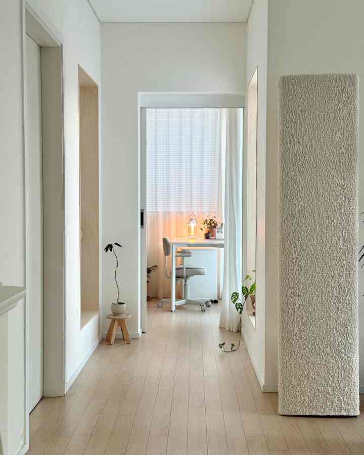White and wood tone small home office featuring a neat desk, office chair, and plants creating a cozy atmosphere