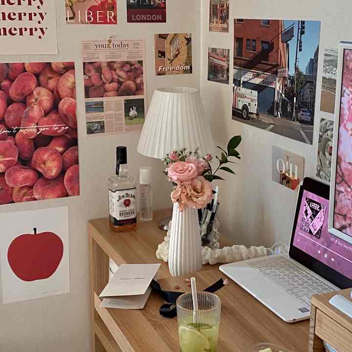 ホワイトと木目調のホームオフィスデスク、花瓶とヴィンテージポスターが配置された雰囲気のある空間