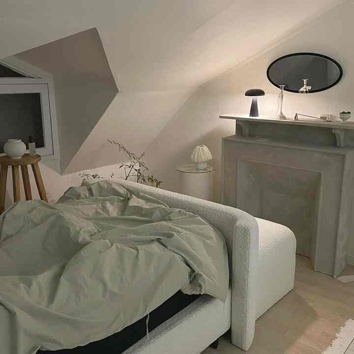 Soft white-toned bedroom featuring a sofa-style bed frame and elegant lighting creating a calm autumn night ambiance