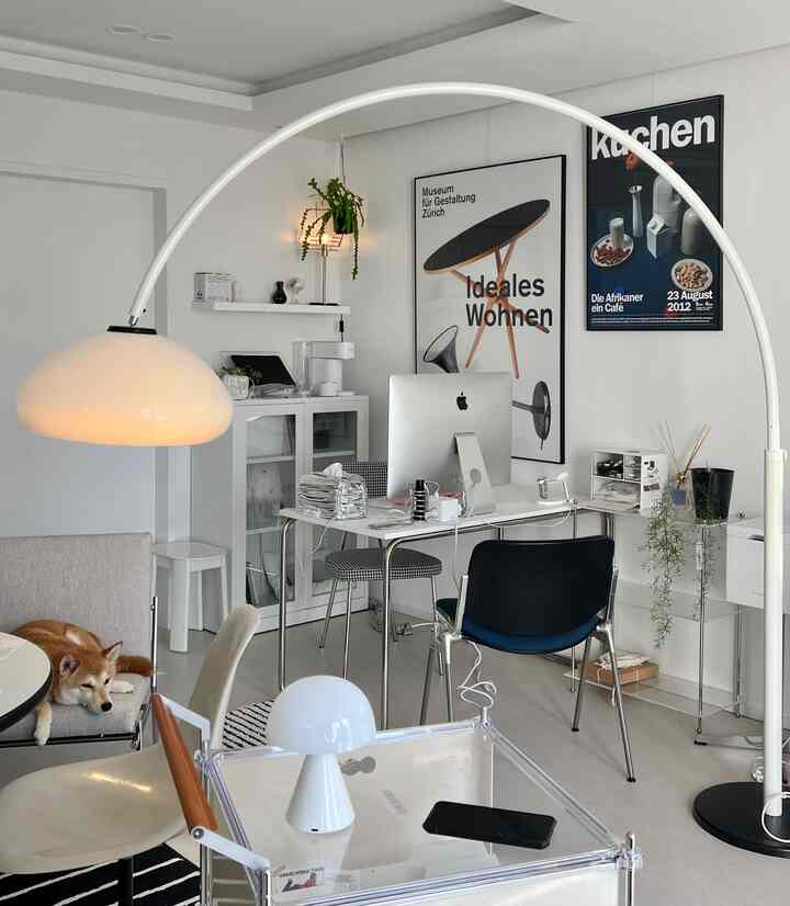 白と黒の色調のホームオフィス、犬がくつろぐラウンジチェアが置かれたミッドセンチュリーモダンスタイルのインテリア