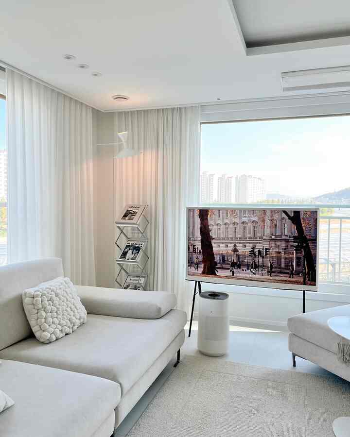 ホワイトトーンのリビング、ラウンジソファと大型テレビ、空気清浄機が配置されたシンプルでモダンな空間