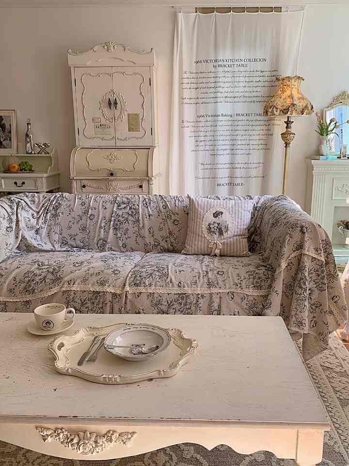 ベージュとアイボリーの色調のリビング、フローラルパターンのソファとアンティーク家具が配置された温かみのある雰囲気のインテリア