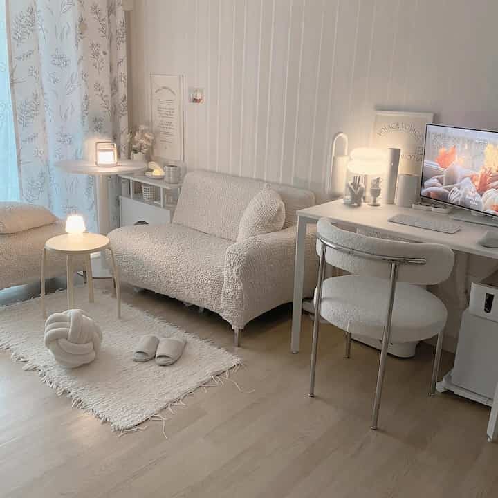 Soft white-toned living room featuring minimal furniture and cozy lighting creating a calm and comfortable atmosphere