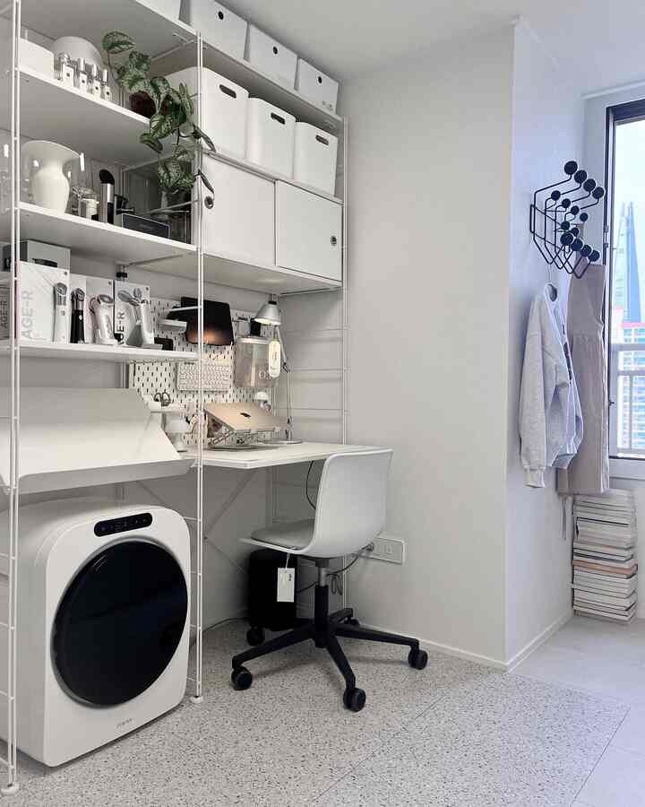 白とグレーのトーンの書斎兼ウォークインクローゼット、ミニ乾燥機とモジュラー収納が配置された雰囲気のあるインテリア
