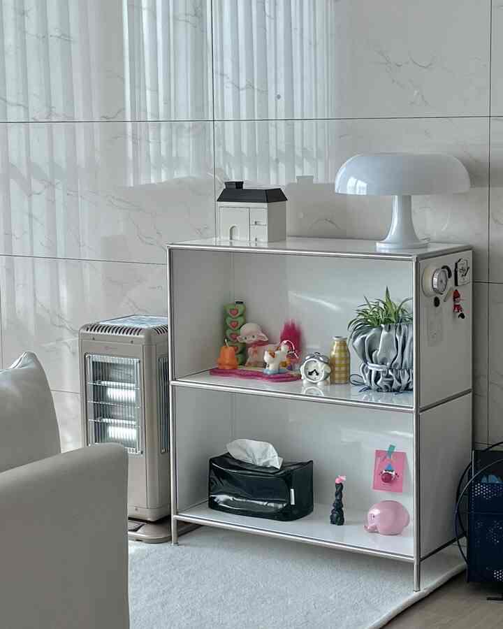 ホワイトとモダンな色調のリビング、かわいい小物やキャンドル、テーブルランプが配置された印象的な空間