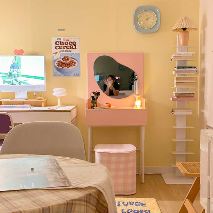 やわらかな黄色の壁とピンクの化粧台があるワンルームのホームオフィス空間