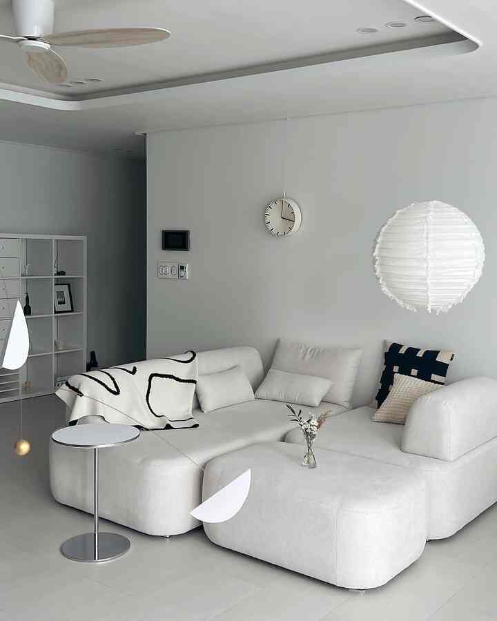 White-toned living room featuring modern sofa and pendant light in a clean, minimalist space