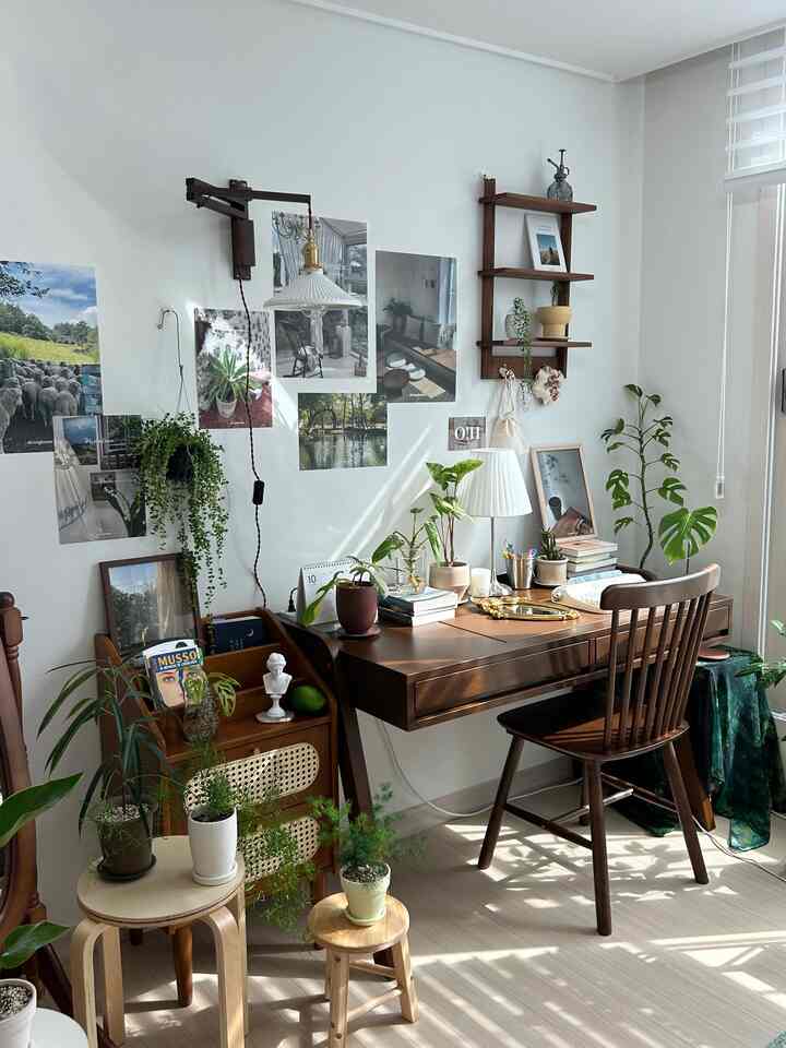 白い壁と木目調のデスク・チェアが配されたナチュラルモダンなホームオフィス、多様な植物が空間に彩りを添える