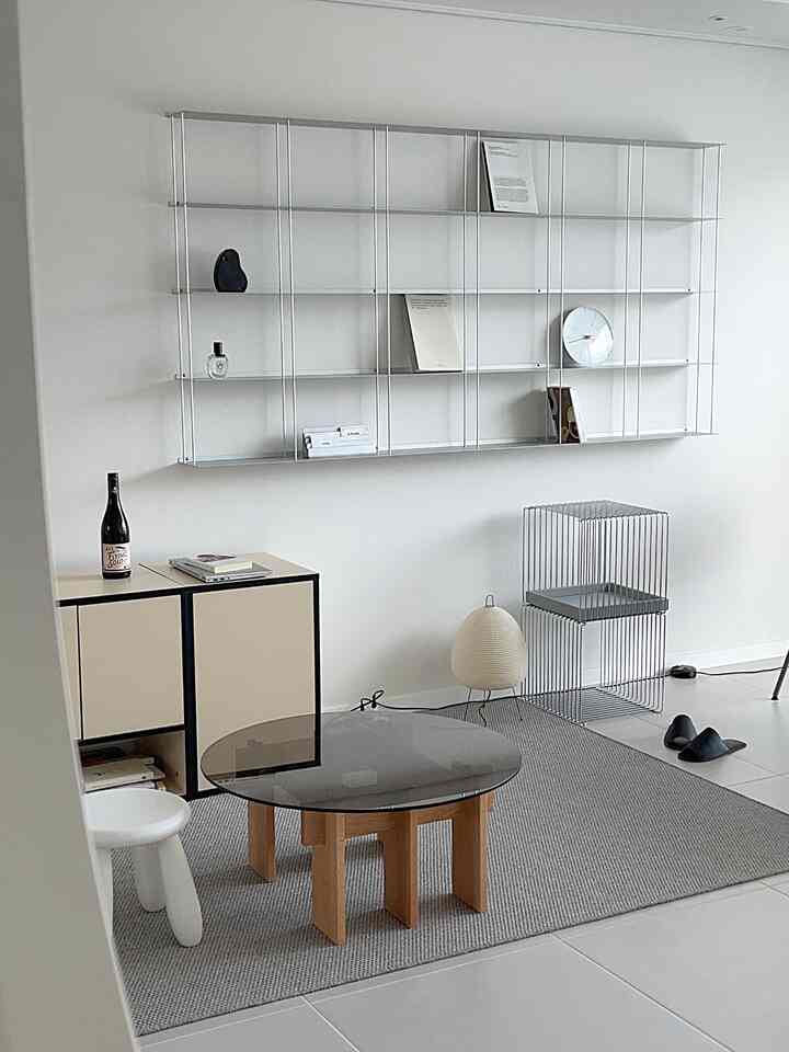 白い壁とグレーのラグ、丸いコーヒーテーブルとミニマルな家具が配置されたモダンなリビングルーム