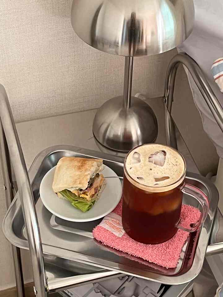 Silver stainless steel trays with table lamp featuring iced coffee mug and sandwich in a cozy home cafe setup