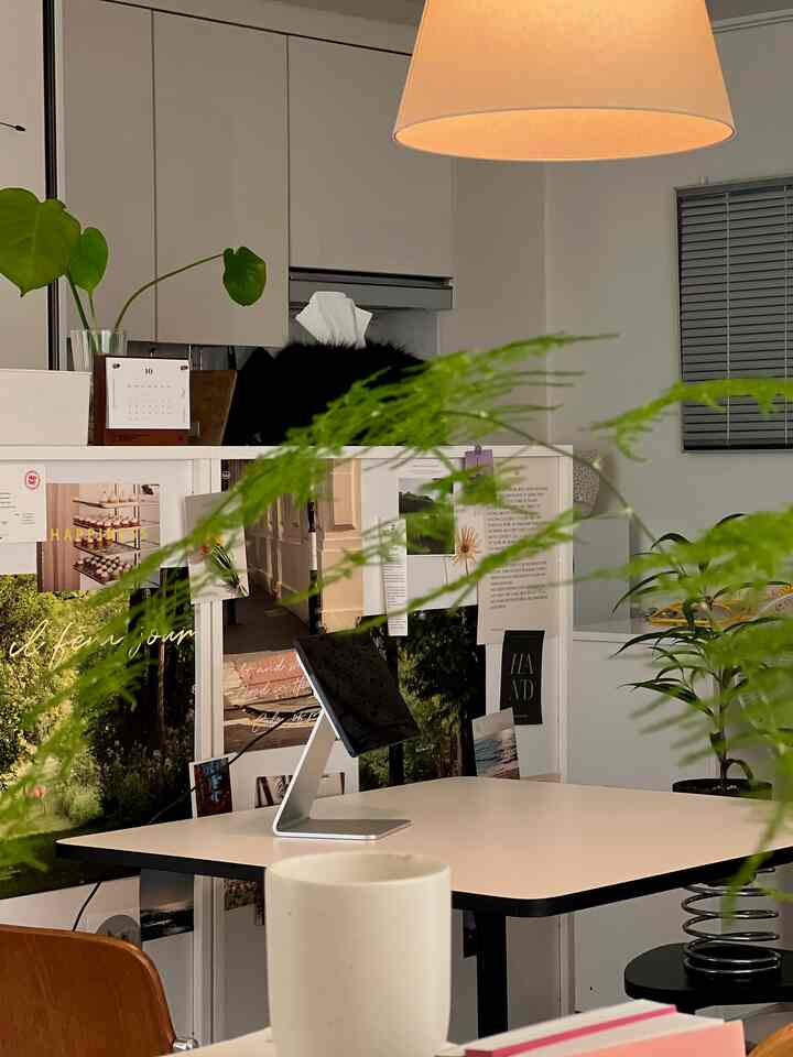 白とナチュラルカラーの調和したホームオフィス、植物とシンプルな家具が配置された落ち着いた在宅勤務の空間