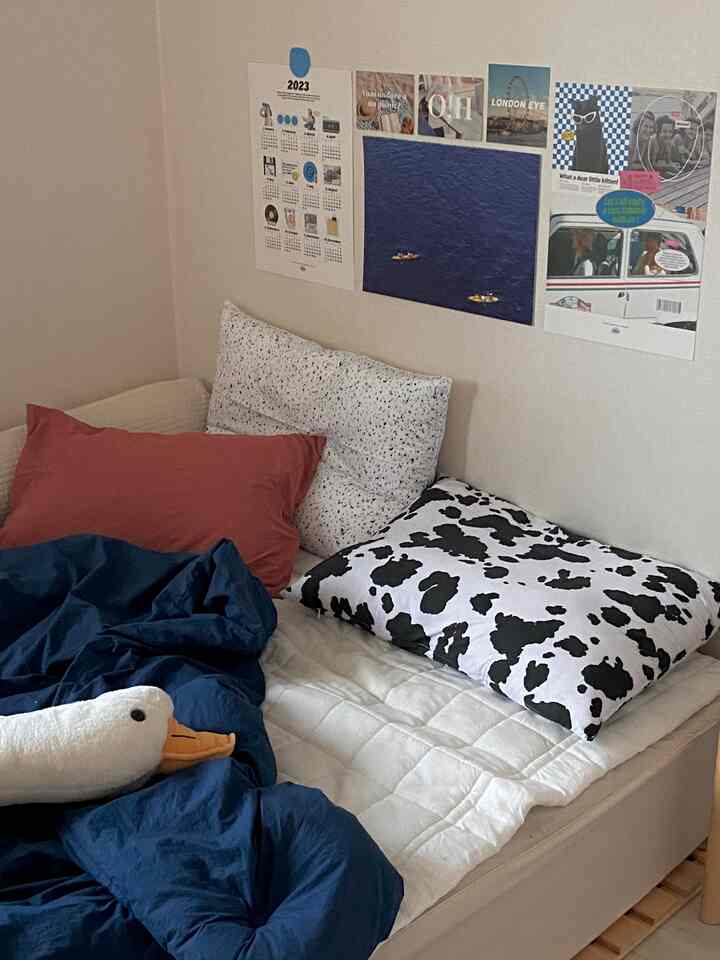 Navy and white toned bedroom featuring patterned pillows and wall posters creating a cozy space