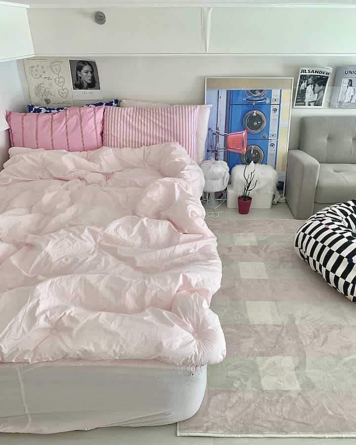 Pink and beige toned studio bedroom featuring pink duvet cover, pillows, and beige sofa creating a warm atmosphere