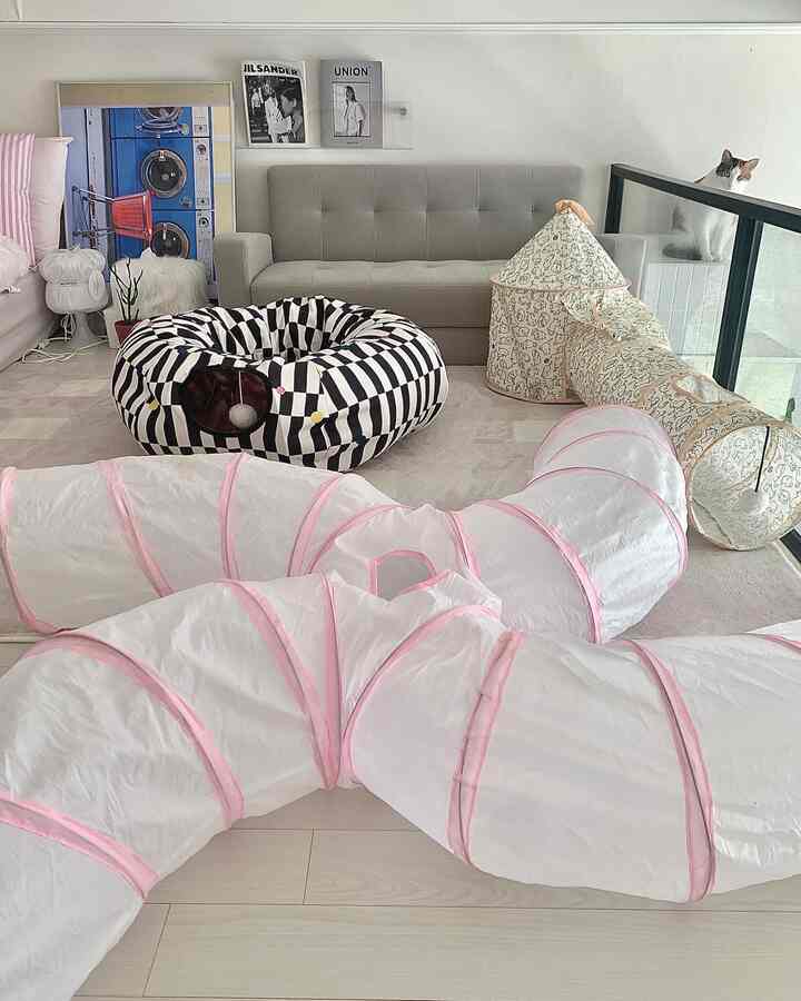 Living room with white and beige tones featuring cat tunnels and house-shaped toys centrally placed for a cozy atmosphere