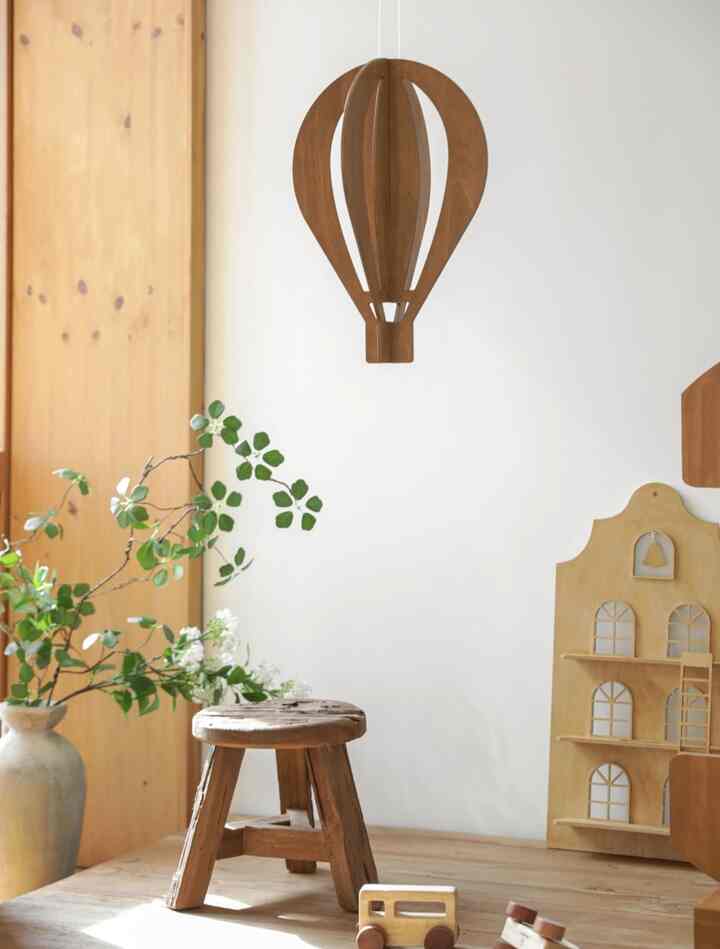 Bright kids' room with white walls and wood-tone furniture, featuring a wooden stool, plants, and toys creating a cozy atmosphere