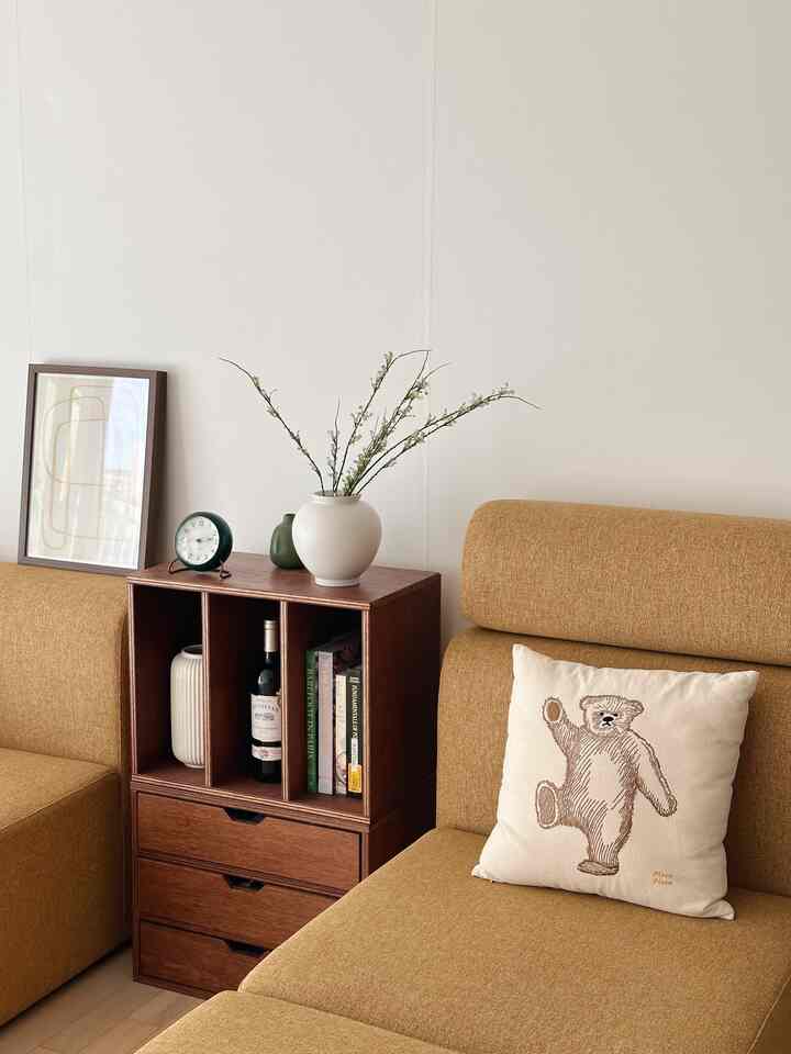 Beige sofa and brown wood-tone side table with white walls create a clean natural modern living room space