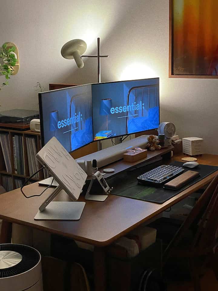 Natural tone home office with dark brown wood desk and dual monitors, featuring focused ambient lighting