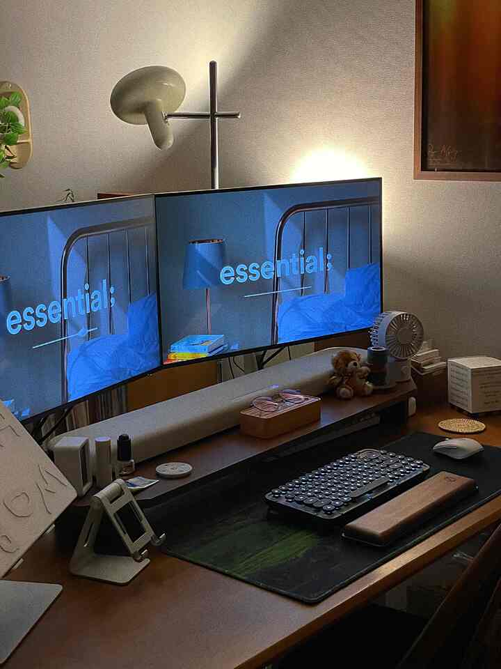 Brown wood-toned home office featuring dual monitors and keyboard with a cozy working atmosphere