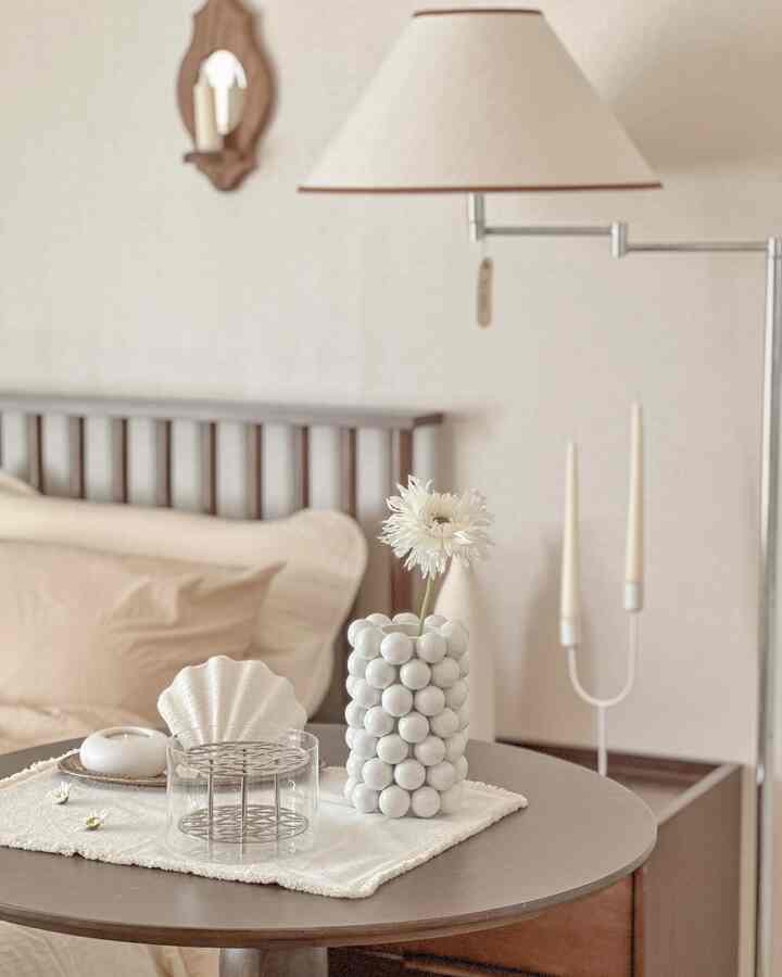 ナチュラルなベージュトーンの寝室、ベッドリネンとベージュのフロアランプが配置された落ち着いた雰囲気のインテリア