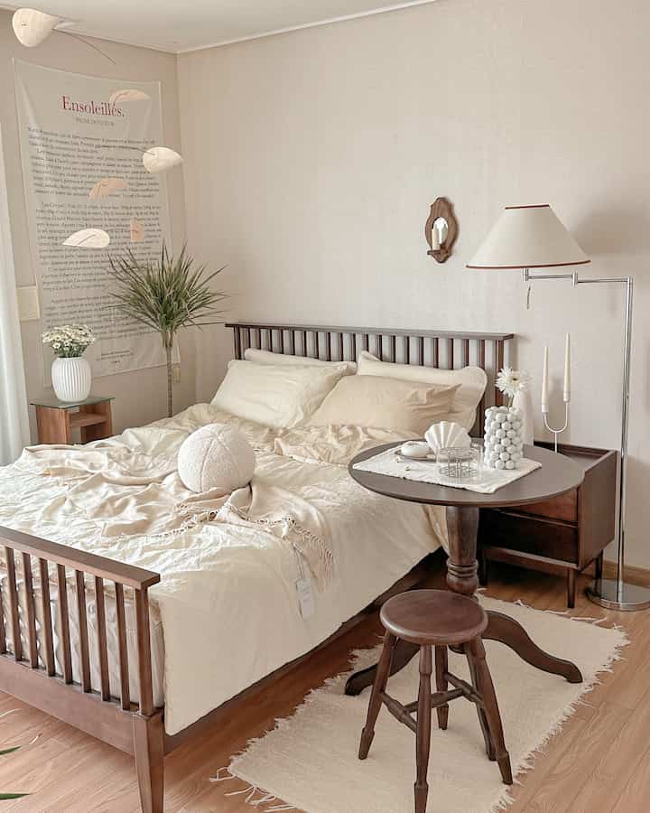 Beige and walnut wood tone bedroom featuring wooden bed, nightstand, and floor lamp with natural warm atmosphere