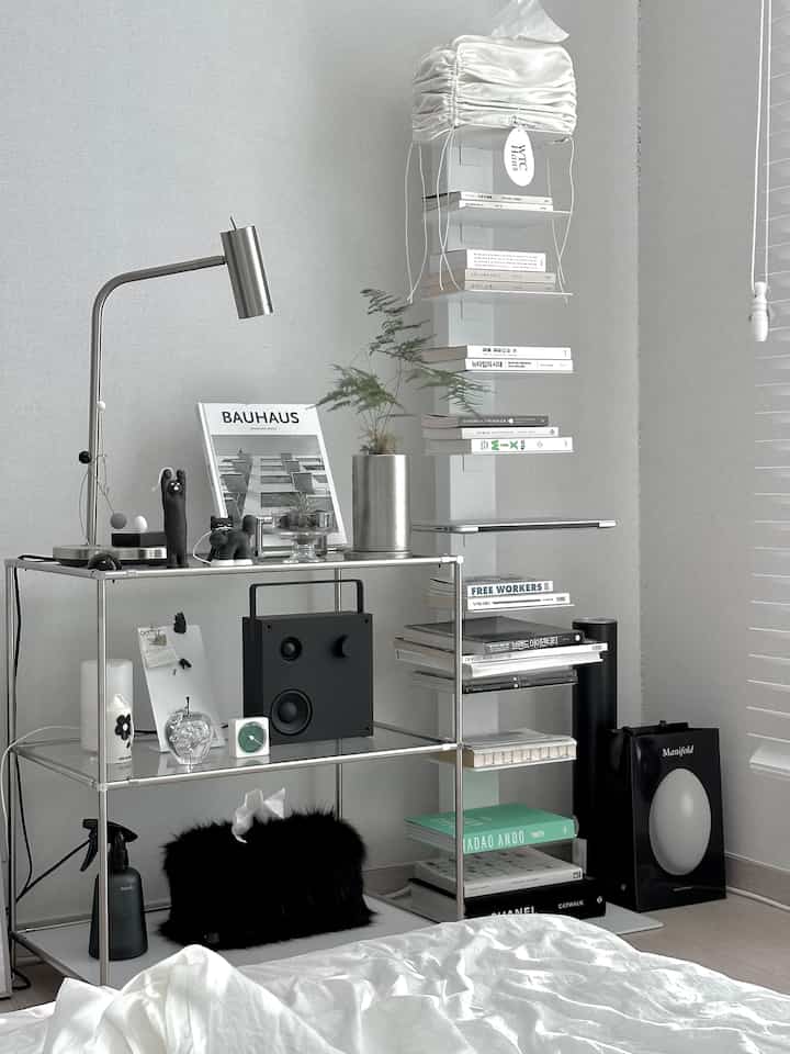 Monotone white and black bedroom featuring steel shelves and a reading lamp in mid-century modern style