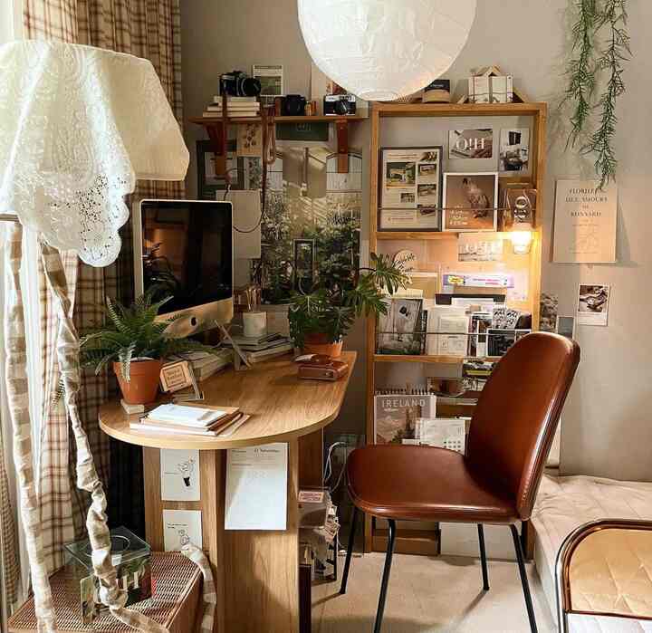木目調と茶色が調和したホームオフィス空間、ヴィンテージポスターとダイニングチェアが配置された雰囲気のあるインテリア