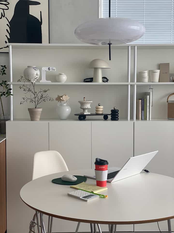 White-toned living study featuring a round table and cabinets, creating a modern and clean atmosphere