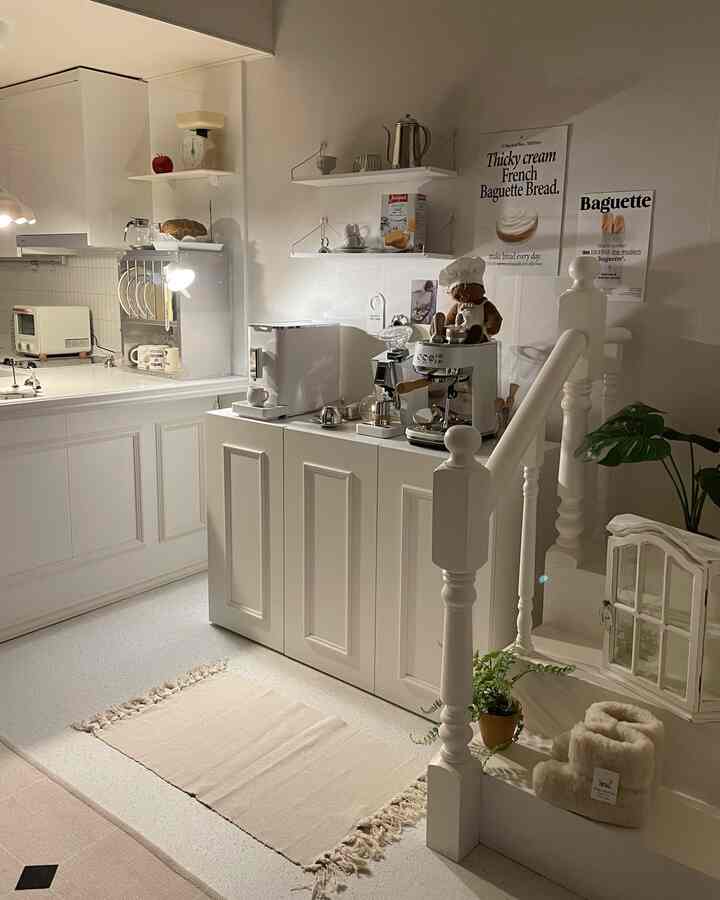 温かみのあるベージュのラグと白い家具が配置された照明のあるワンルームのキッチンおうちカフェゾーン