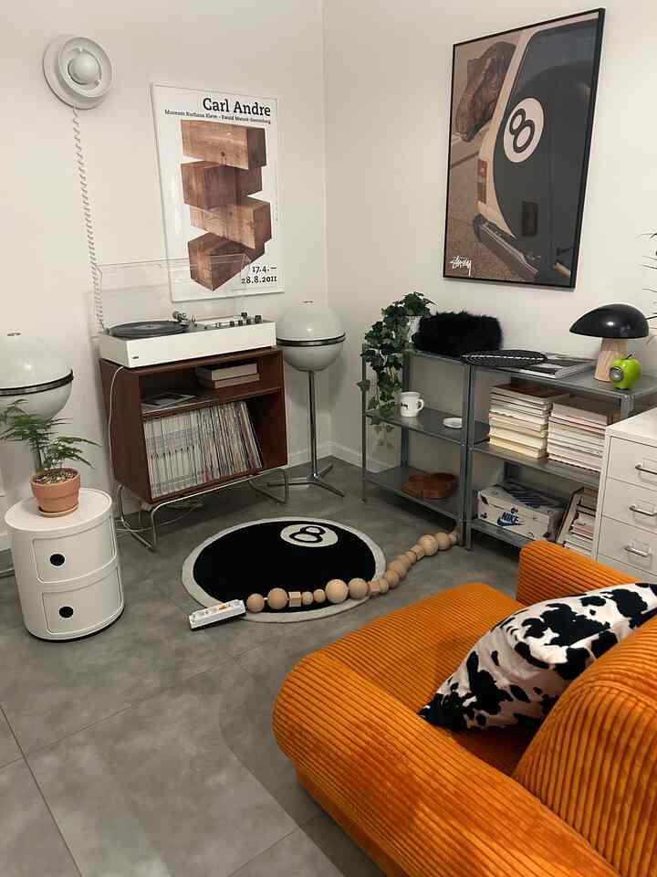 Natural-toned living room with orange sofa and 8-ball rug, featuring retro vintage style elements