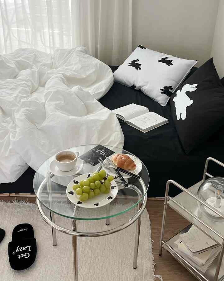 モダンなブラックのソファベッドとホワイトの寝具が配置されたワンルームのおうちカフェ空間