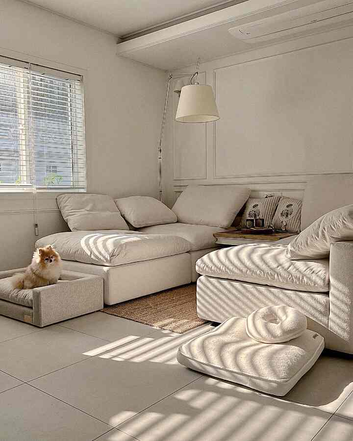 白を基調としたリビングにアイボリーのコーナーソファとペット用ベッドが配置された、落ち着いた自然な雰囲気のインテリア