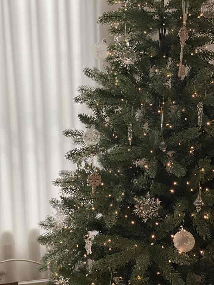 ナチュラルカラーとホワイトトーンのクリスマスツリーにオーナメントとストリングライトが飾られた雰囲気のあるインテリア