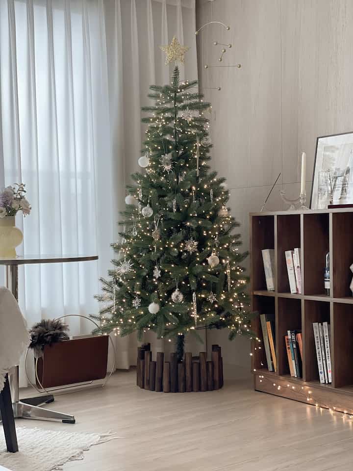 白と木目調が調和するリビング、飾り付けられたクリスマスツリーとゴールドのモビールが配置された温かみのあるインテリア