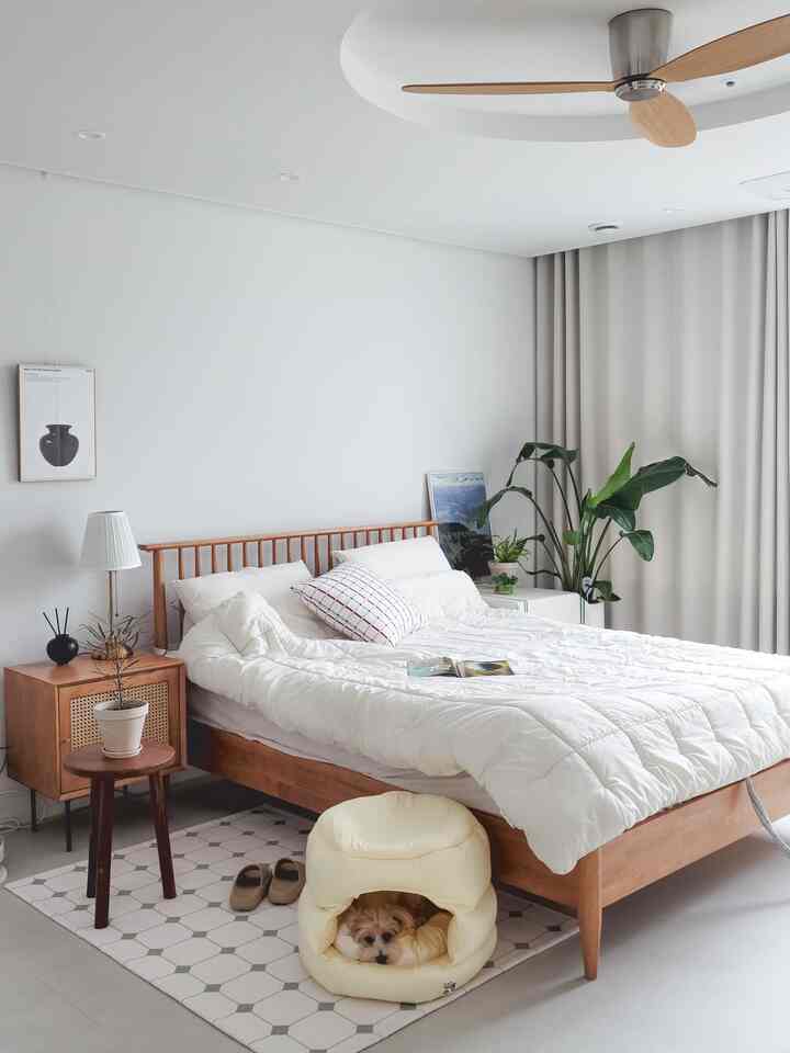 ホワイトとウッドトーンの寝室空間、木製家具と植物が配置されていて、温かみのある自然な雰囲気のインテリア