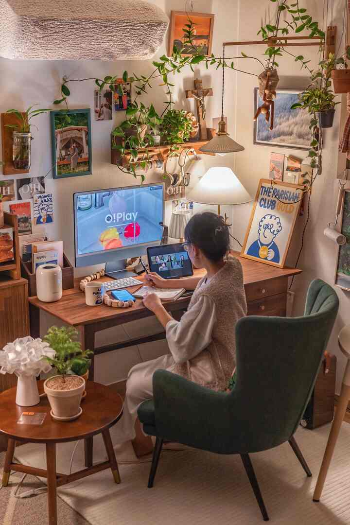 ナチュラルなウッドトーンと緑の植物が調和する、快適なアームチェアと温かみのある照明が配されたホームオフィスの雰囲気あるインテリア