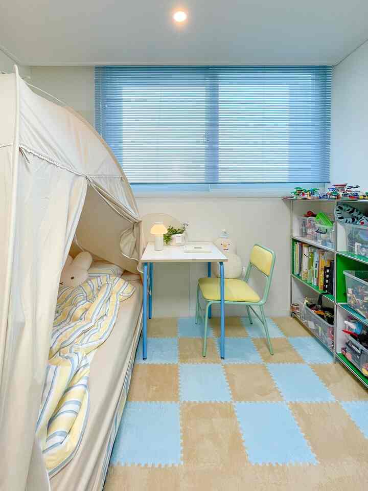 ブルーとベージュの色調の子供部屋、小さな机と椅子、おもちゃ収納が配置された雰囲気のあるインテリア