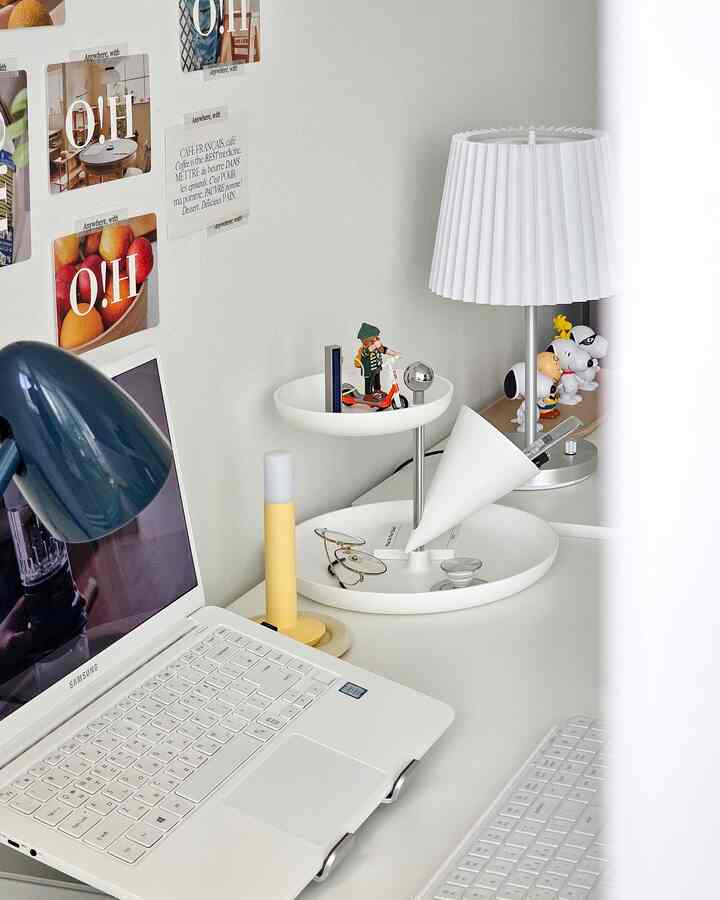 White-toned home office desk featuring playful Playmobil figures and desk lighting in a clean, simple setting