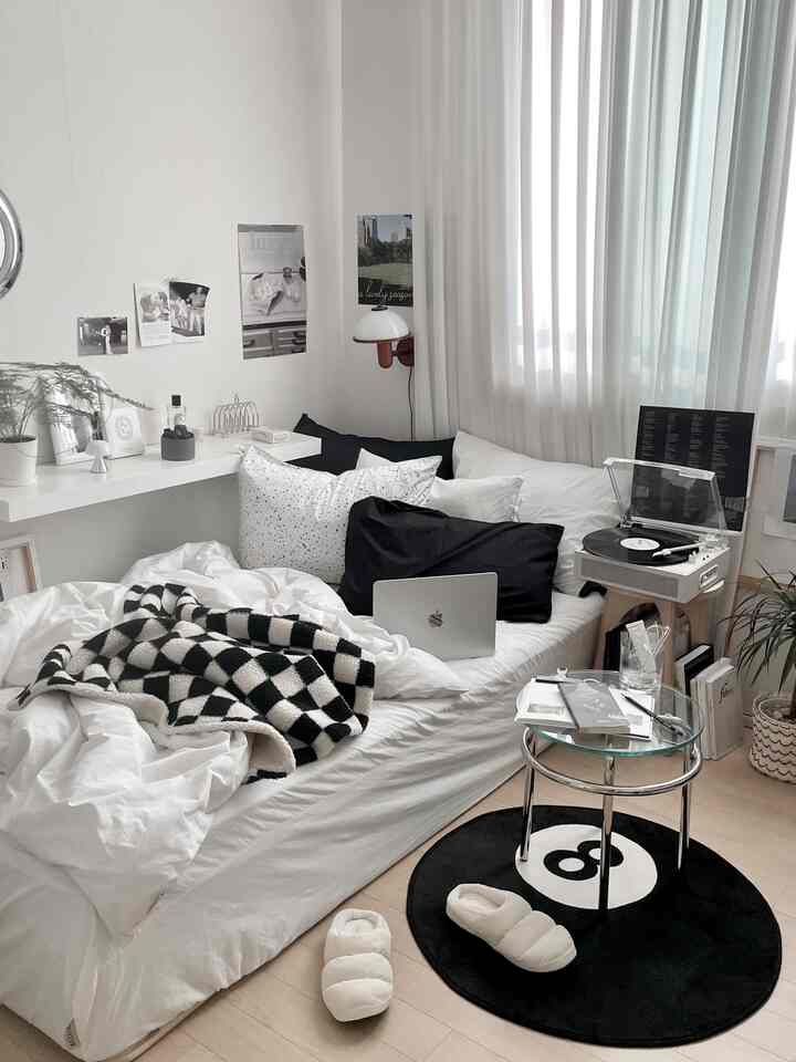 白と黒のモノトーンの寝室、窓際にカーテンとターンテーブルが配置されたモダンで落ち着いた空間