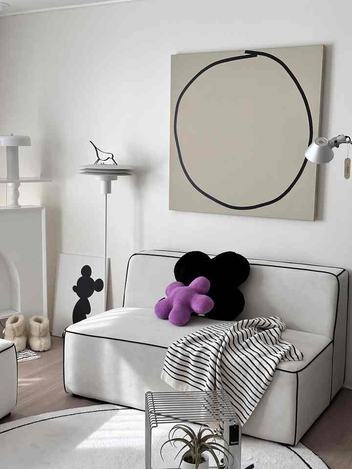 White and natural tone living room featuring a modern sofa with cushions and a round rug creating a clean atmosphere