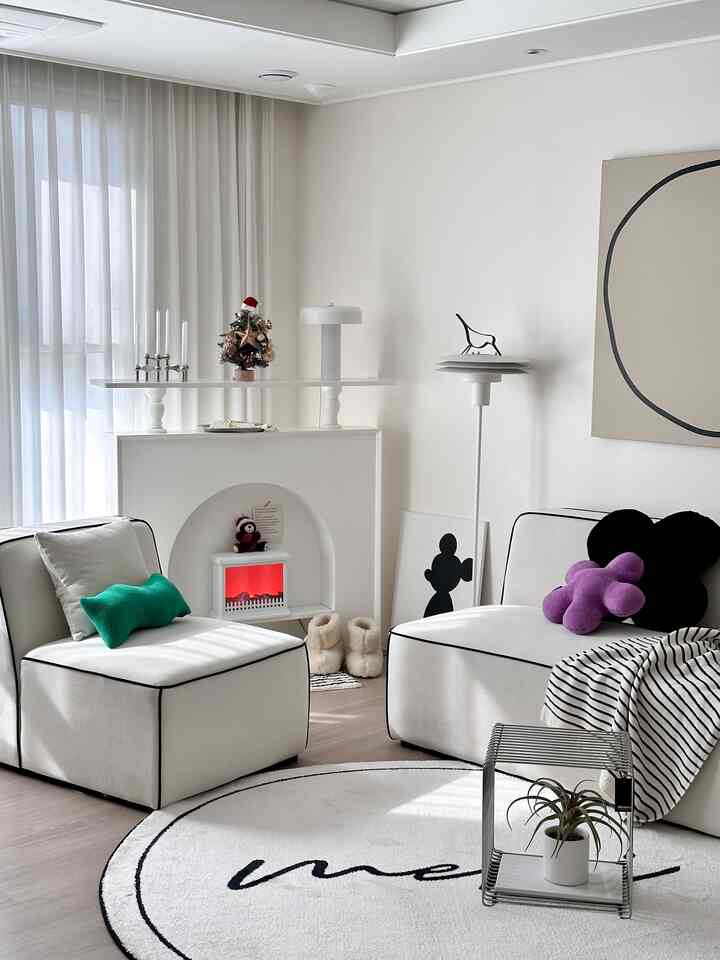 White-toned living room featuring modular sofas and a mini Christmas tree, creating a simple and warm atmosphere