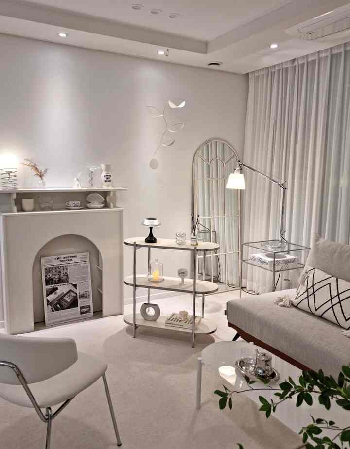 White-toned living room featuring a minimalist shelf, standing lamps, and a modern sofa creating a cozy atmosphere