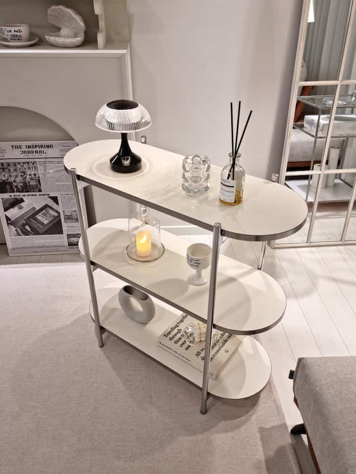 White-toned living room featuring a 3-tier modular shelf with various objets styled in a modern minimalistic way