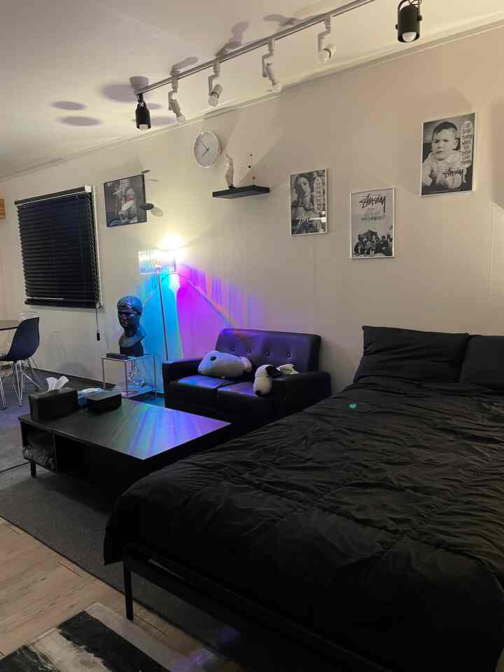 ブラックトーンの1.5ルーム寝室、中央にソファとコーヒーテーブル、黒のベッドが配置されたモダンなインテリア